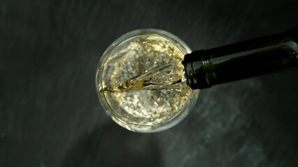 Wall Mural - Super slow motion of pouring white wine, black stone background. Top view. Filmed on a high speed cinema camera at 1000 fps.