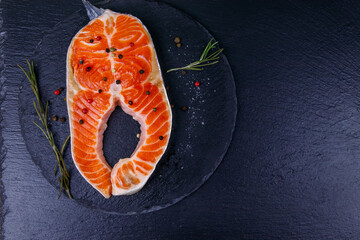 Wall Mural - Raw salmon steak with spices on black slate. Top view