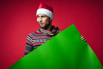 Wall Mural - handsome man in a santa hat holding a banner holiday studio posing