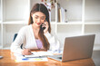 © Daenin - Businesswoman or accountant using the phone to check business information. Accounting Documents and Laptop at Small Office Business Ideas