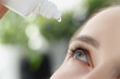 Woman dripping moisturizing drops into her eye closeup