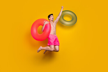 Poster - Full body profile side photo of young man happy positive smile jumper air inflate bathing sea isolated over yellow color background