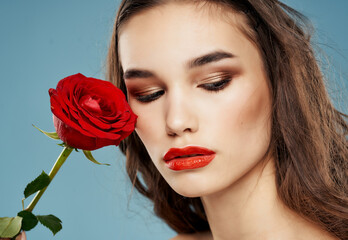 Wall Mural - attractive woman and red lips rose flower close-up blue background