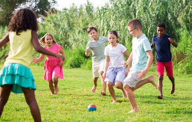 Wall Mural - Positive kids running on field and playing football together.