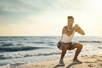 Poster - Sporty man doing exercise on sandy beach at sunset