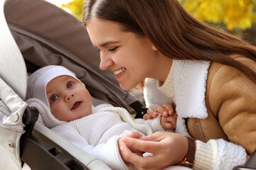 Canvas Print - Happy mother with her baby daughter in stroller outdoors on autumn day