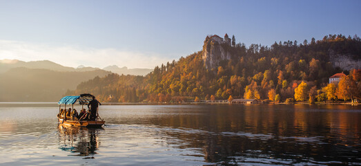 Wall Mural - Traditional wooden boat on beautiful Bled lake, Slovenia at sunset.