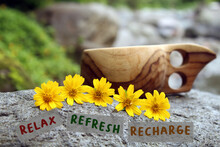 Relax - Recharge - Refresh. Self Love Care And Healing Concept With Natural Traditional Wooden Cup And Yellow Tiny Flowers On A Stone Outdoor.