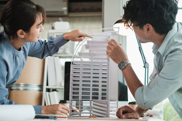 Team architects or engineer designer in office discussing construction project. Young male and female architect working together on new building model. Selective focus.