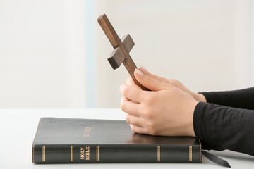 Woman with cross and Holy Bible at table, closeup