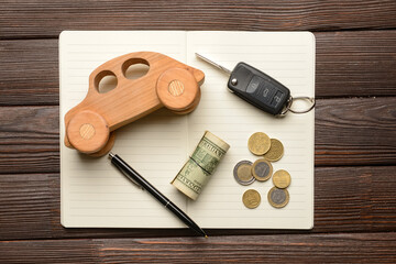 Wall Mural - Wooden car with money, key and notebook on dark wooden background