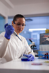Wall Mural - physician researcher dropping liquid in medical glassware using micropipette analyzing coronavirus v