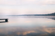 © Siniehina - General plan of the pier for fishermen, which is located on a misty lake. The mist on the water creates the feeling of a magical effect. Clouds bounce off the surface. Place for text