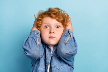 Photo of scared nervous guilty ginger kid touch head speechless wear jeans jacket isolated blue color background