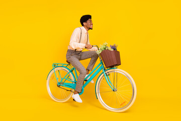 Wall Mural - Profile photo of cheerful african guy ride bicycle toothy smile wear suspenders shirt isolated yellow color background