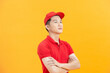 Smiling young handsome asian delivery man in red uniform standing with arm crossed
