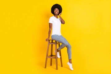 Sticker - Photo of pretty cute dark skin lady wear white t-shirt arm hairdo sitting bar chair looking empty space isolated yellow color background