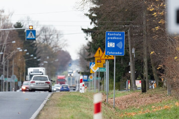 Szadki, Poland - November 5, 2021: Speed camera at the pedestrian crossing in front of the intersection. Information signs about speed measurement in built-up areas. Safety on the road.