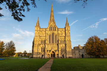 Salisbury, Wiltshire, England, UK. 2021. Salisbury Cathedral, west front seen with glow of the setting sun and a blue sky.