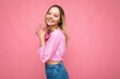 © Ivan Traimak - Photo of young positive happy smiling attractive blonde woman with sincere emotions wearing pink blouse isolated on pink background with empty space and making shooting hand gun