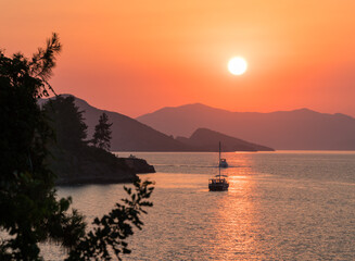 Wall Mural - calm sea and sunset. sun is setting behind the hills on the horizont. beautiful nature background.