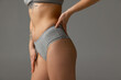 © master1305 - Cropped image of sportive female body in cotton gray panties isolated on light grey studio background. Natural beauty concept.