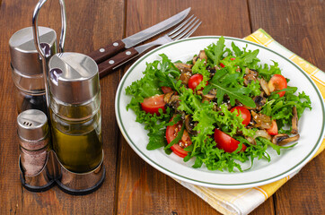 Wall Mural - Diet salad of arugula leaves, tomatoes and fried mushrooms on wooden table. Studio Photo