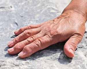 Close Up hand of senior woman on stone background. arthritis, osteoporosis, rheumatism concept.