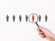 © Ekahardiwito - Hand holding magnifier with employee icons. Choosing the right pertner or staff concept.