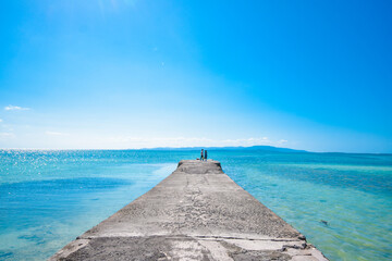 Beautiful clear blue sky and the blue ocean at Taketomi island Pier, Okinawa, Japan. Pier with the horizon. Ocean with corals.