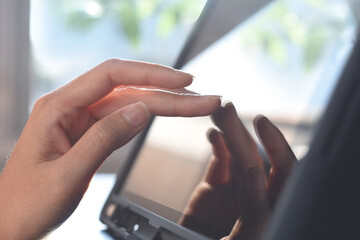 Close up of business woman hand using digital tablet computer surfing the internet, finger touching on tablet screen with reflection on office table, close up