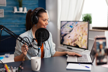 Canvas Print - Woman in home studio recording podcast with mobile phone. Vlogger using headphones, microphone and laptop to stream online vlog. Content creator broadcasting with smartphone for social media.