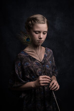 Studio Portrait Of Classic Girl Holding Peacock Feather In Blue Dress