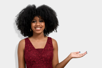 Wall Mural - portrait of a dark-skinned girl with afro haircut, points with her front fingers, shows blank space for her promotion, isolated on gray background People, advertising concept