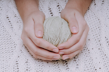 Aufkleber - brown ball of wool in hands on the background of a white knitted tablecloth