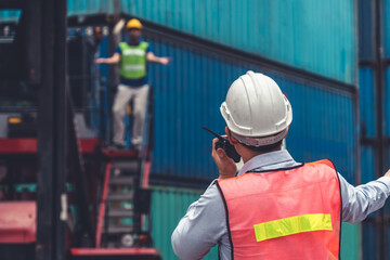 Wall Mural - Industrial worker works with co-worker at overseas shipping container yard . Logistics supply chain management and international goods export concept .