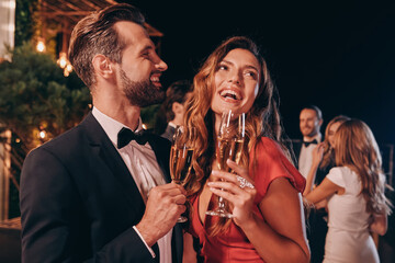 Beautiful young couple in formalwear toasting with champagne while spending time on luxury party