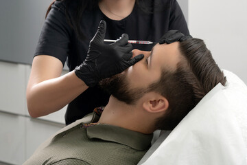 Beauty injections into young male face. Smoothing of mimic wrinkles using biorevitalization for man