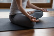 © fizkes - Close up cropped image young slim woman wear grey sportswear meditating sit cross-legged on mat. Stress relief, renew energy after yoga practice, sport training, mindfulness, healthy lifestyle concept