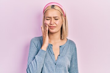 Poster - Beautiful blonde woman standing over pink background touching mouth with hand with painful expression because of toothache or dental illness on teeth. dentist