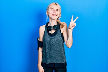 Poster - Beautiful caucasian woman with blond hair wearing sportswear showing and pointing up with fingers number two while smiling confident and happy.