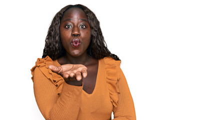 Poster - Young african woman wearing casual clothes looking at the camera blowing a kiss with hand on air being lovely and sexy. love expression.