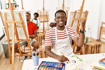 Sticker - Young african man at art studio screaming proud, celebrating victory and success very excited with raised arms