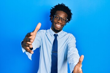 Poster - Young african american man wearing business clothes looking at the camera smiling with open arms for hug. cheerful expression embracing happiness.