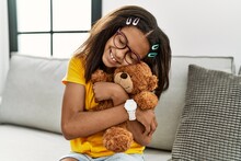African American Girl Smiling Confident Hugging Teddy Bear At Home