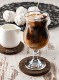 Fototapeta Mapy - Pouring milk into coffee in drinking glass, iced coffee drink