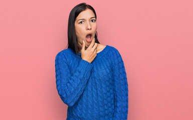 Wall Mural - Young hispanic woman wearing casual clothes looking fascinated with disbelief, surprise and amazed expression with hands on chin