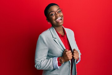 young african american woman wearing business jacket and glasses winking looking at the camera with 