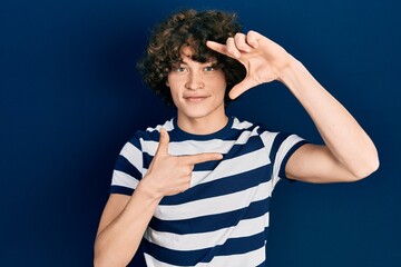 Handsome young man wearing casual striped t shirt smiling making frame with hands and fingers with happy face. creativity and photography concept.