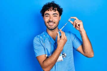 Sticker - Young hispanic man wearing nurse uniform holding vaccine smiling with a happy and cool smile on face. showing teeth.